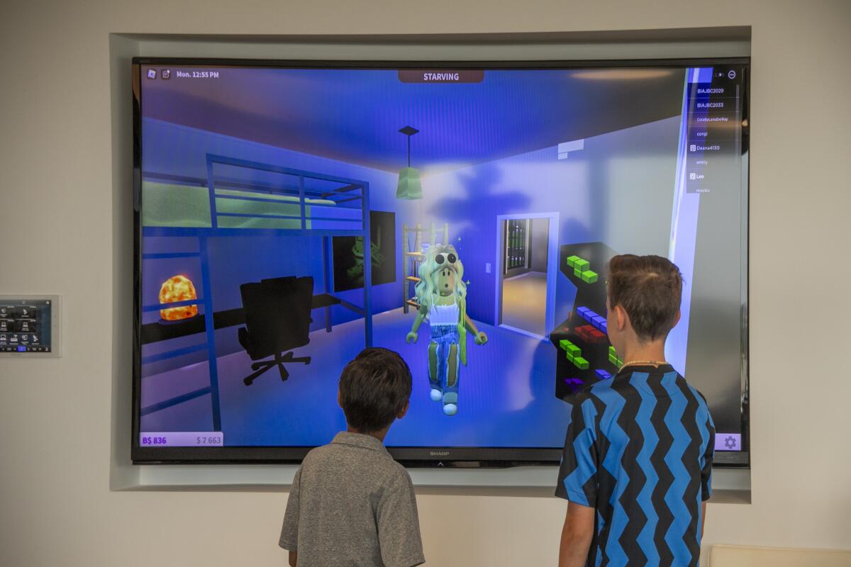 Leyton Mireles, left, and Everett Gredler watch an animated character explore a virtual house they designed together.