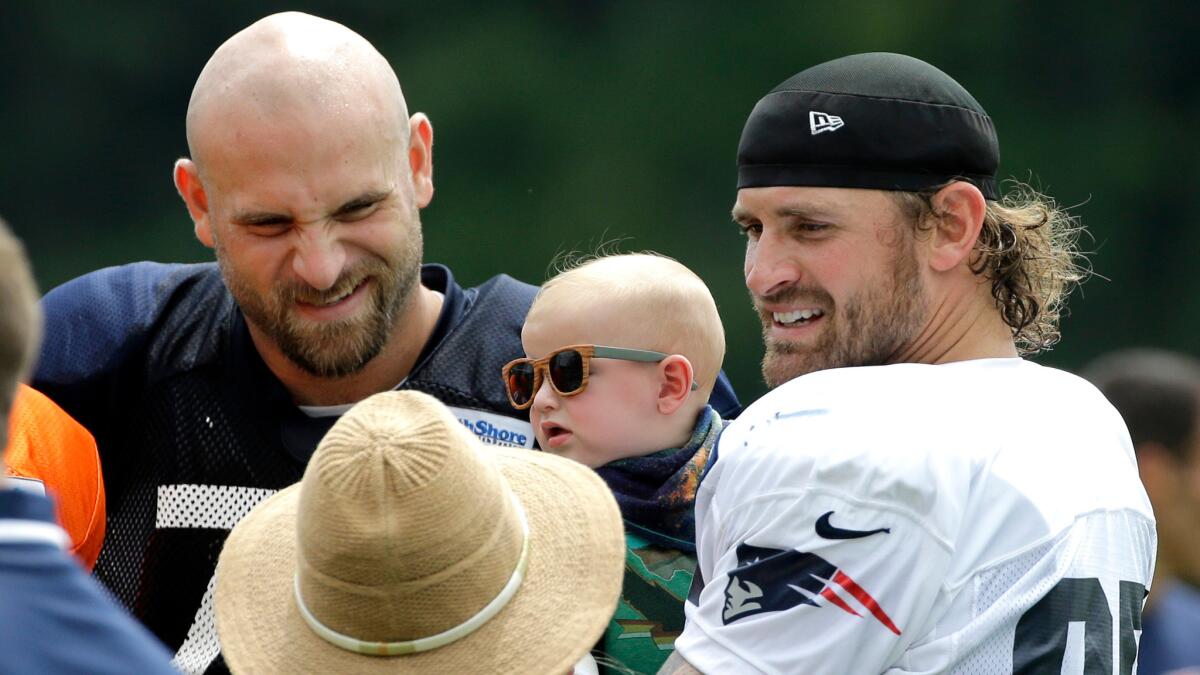 New England defensive end Chris Long, right, holds his 5-month-old son, Waylon, while spending time with his brother, Chicago Bears offensive tackle Kyle Long, at training camp on Aug. 16.