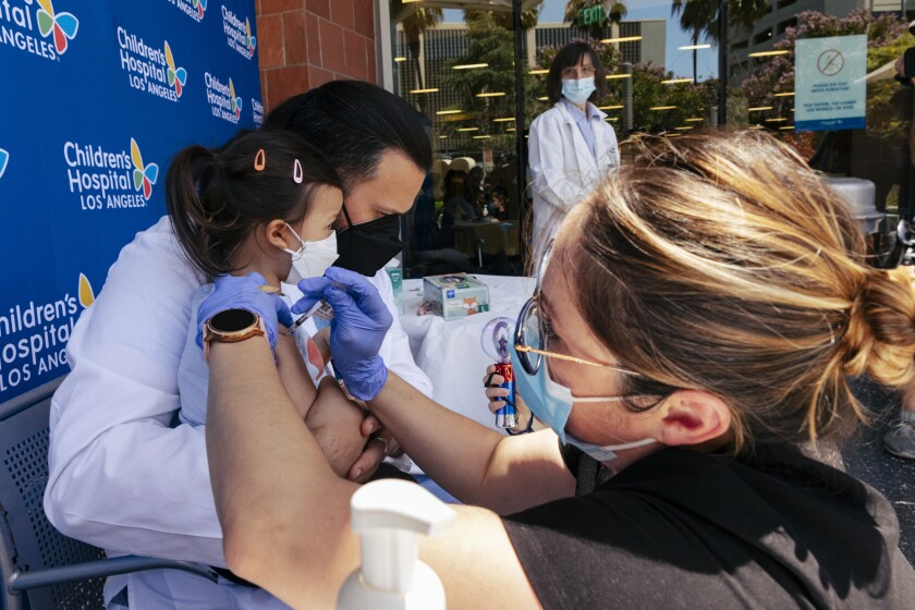 A nurse gives a young girl a shot