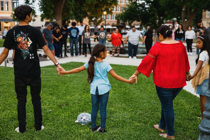 Adults and children holding hands at a prayer vigil