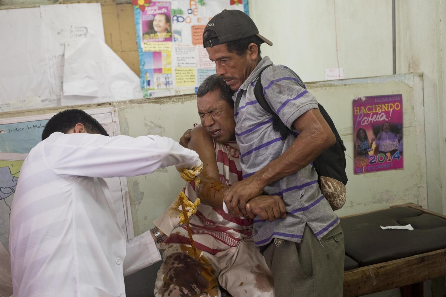 Rosman Flores, miembro del consejo de ancianos del pueblo miskito, es sostenido por un amigo mientras el doctor retira un proyectil que lo hirió en un enfrentamiento armado en Waspam, Nicaragua.