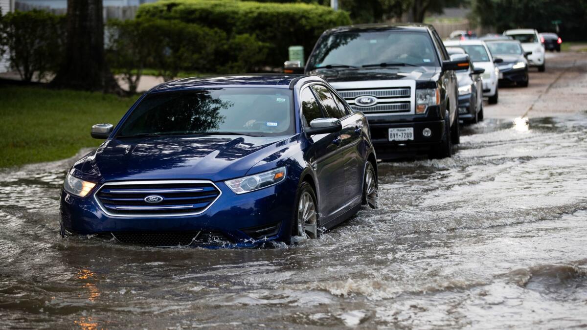 Vehicles drive through floodwaters in Texas in the aftermath of Hurricane Harvey. Automakers reported strong sales of replacement vehicles in September.