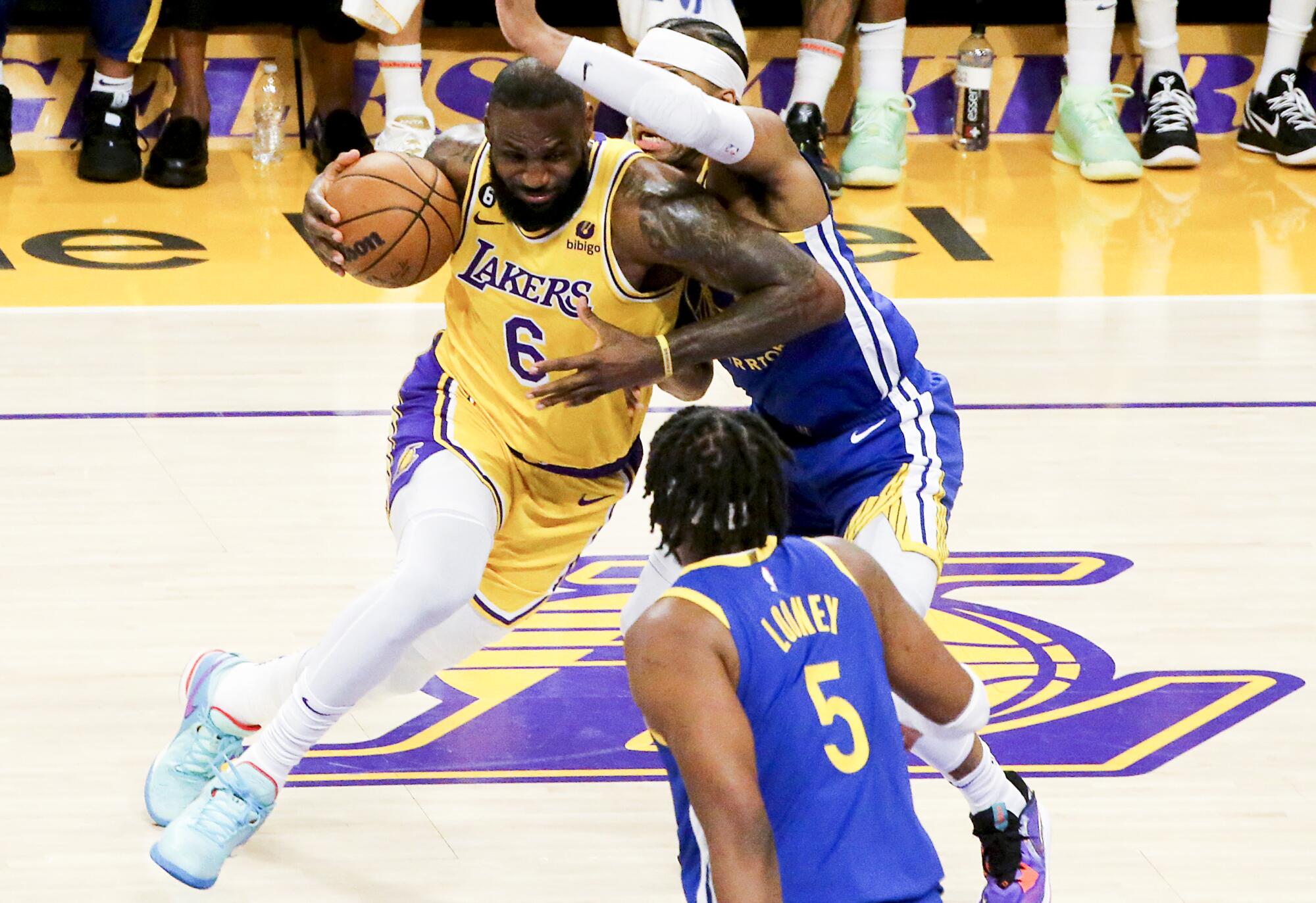  Lakers star LeBron James, left, drives to the basket past Warriors guard Moses Moody during the first half.