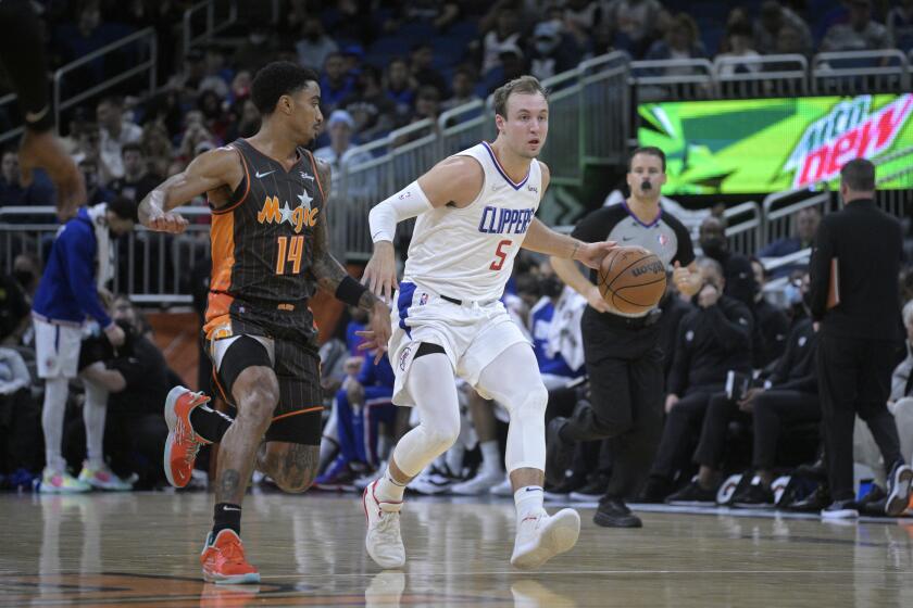 Los Angeles Clippers guard Luke Kennard (5) brings the ball up the court while defended by Orlando Magic guard Gary Harris (14) during the first half of an NBA basketball game, Wednesday, Jan. 26, 2022, in Orlando, Fla. (AP Photo/Phelan M. Ebenhack)