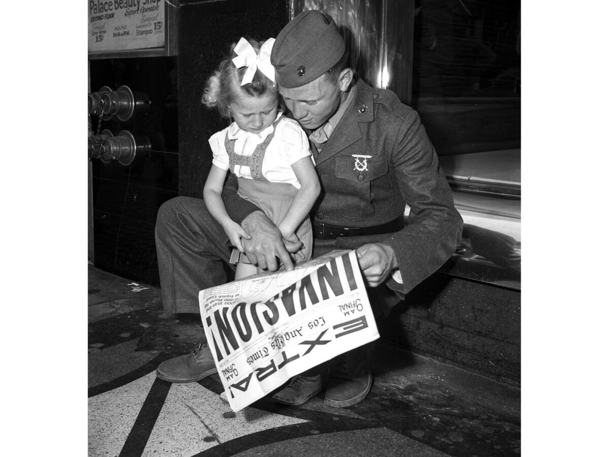 June 6, 1944: Marine Pvt. Calvin H. Laxson shows the invasion map to his daughter Cathryn, 3.