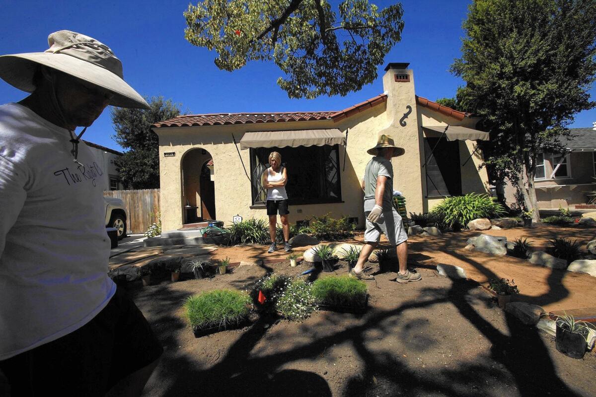 Brian Dines, left, and his wife, Nora, look over their Long Beach yard after their lawn's removal last summer. Landscape designer John Royce, right, worked up a meadow theme with drought-resistant plants.