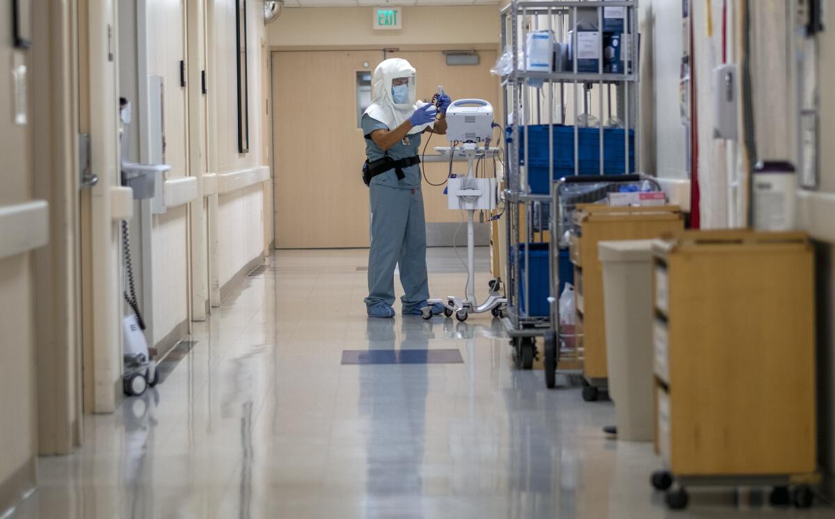 A certified nursing assistant cleans equipment at a hospital COVID-19 unit.