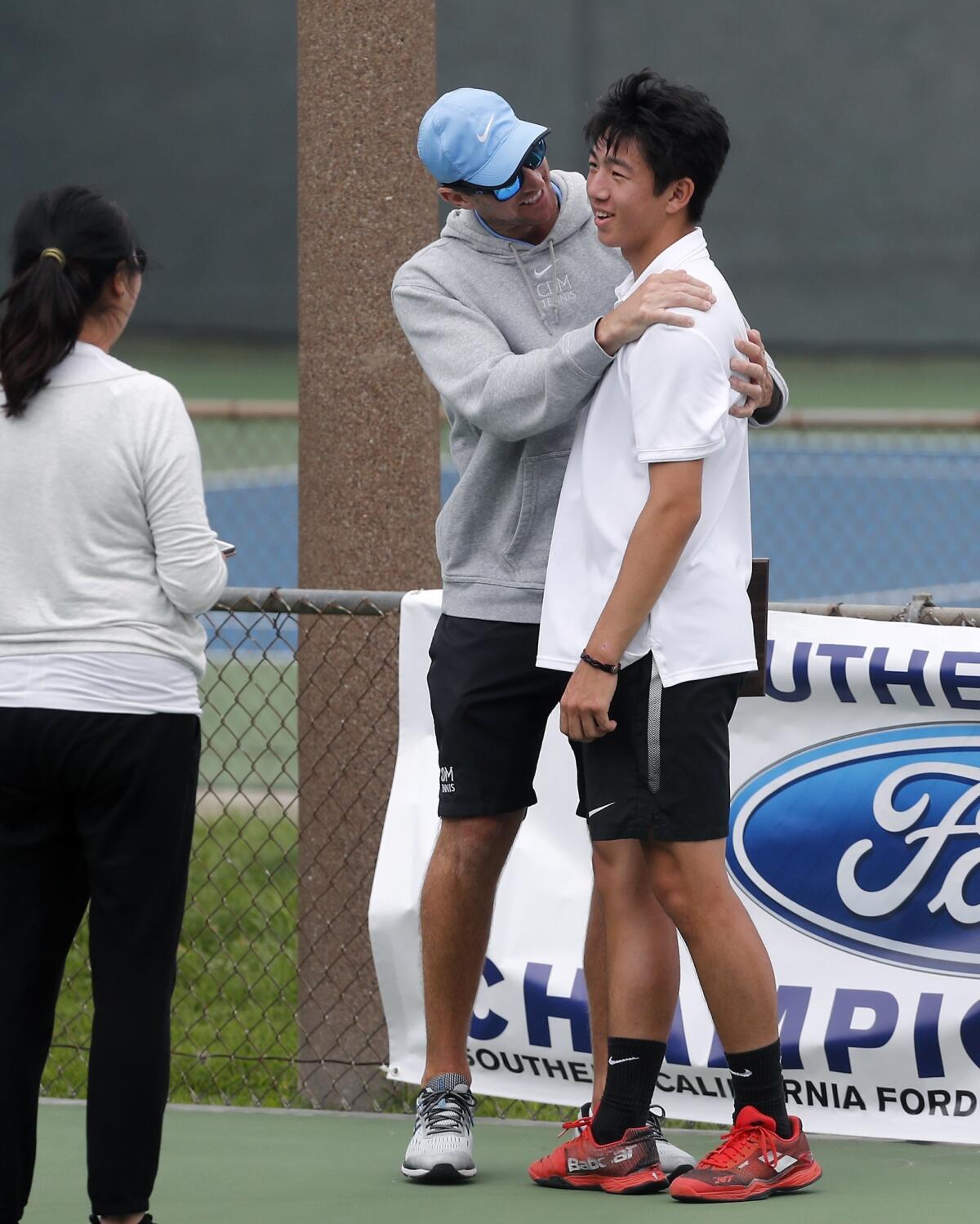 Corona del Mar coach Jamie Gresh, left, congratulates Kyle Pham, right, for his runner-up finish in the CIF Southern Section Individuals tournament on Thursday at Seal Beach Tennis Center.