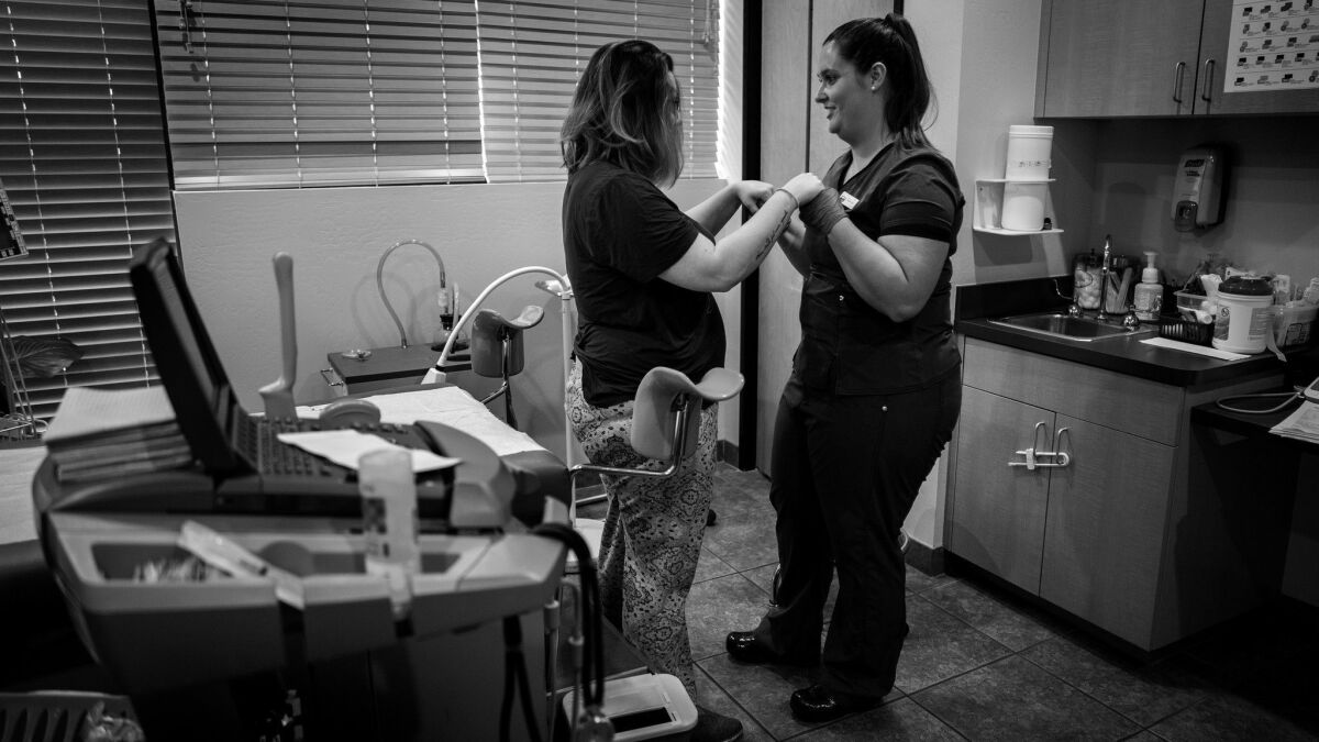 A nurse assists a patient after an abortion procedure at a clinic in Phoenix. The clinic is another that depends on doctors who travel from California.