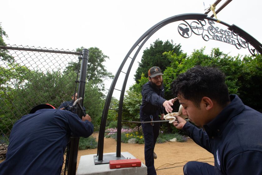 Workers secure a new archway to the entrance of the Secret Garden in Huntington Central Park Friday.