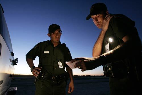 As the sun sets at the southern New Mexico Border Patrol Academy training grounds, Trevino (left) and Gilcher radio in the details of their detention of an illegal immigrant, played by Gonzales.