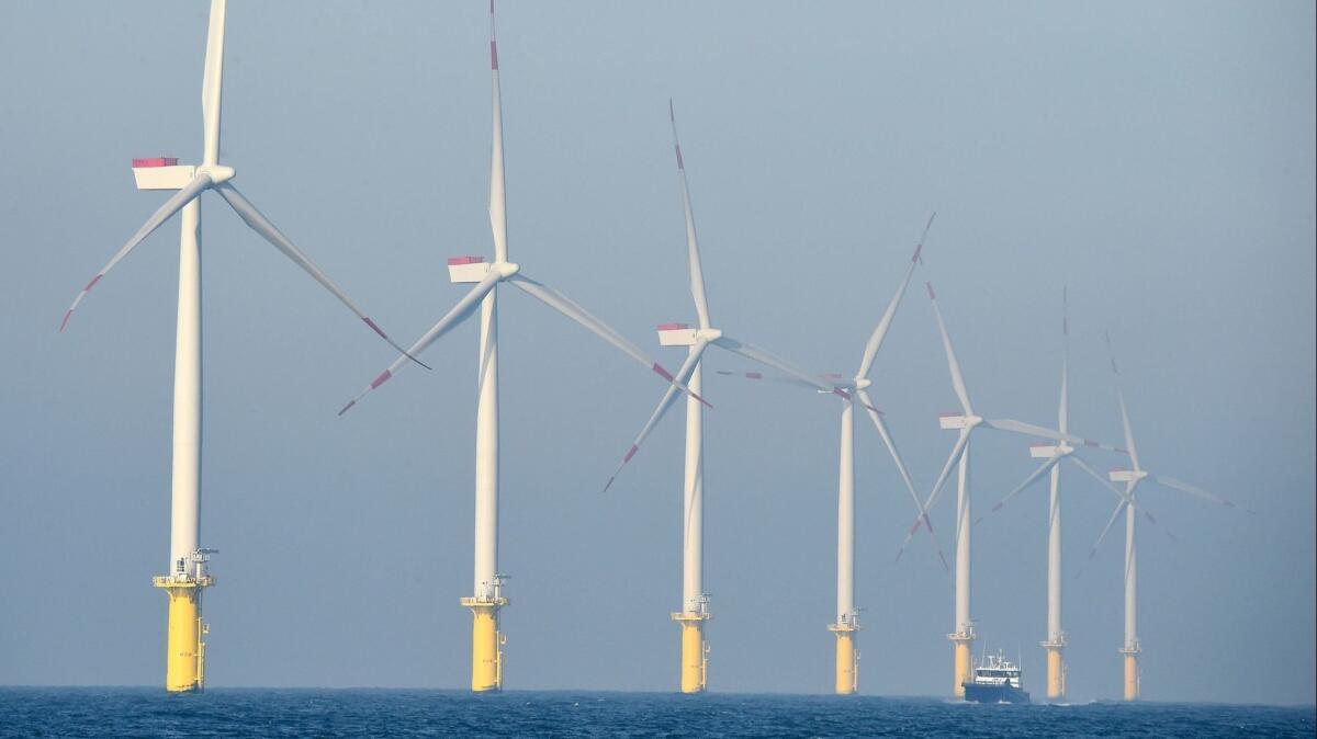 A service vessel passes below wind turbines of the German offshore wind farm Amrumbank West.