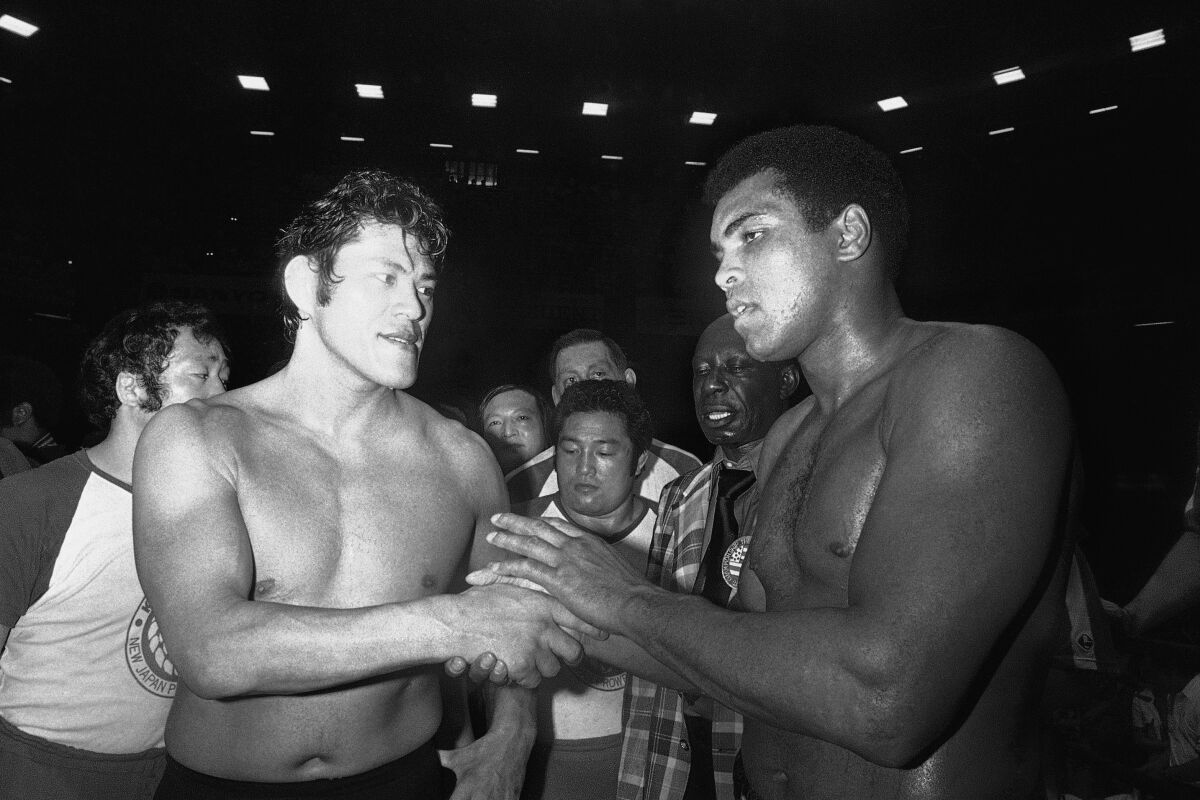 FILE - Wrestler Antonio Inoki, left, and world heavyweight boxing champion Muhammad Ali shake hands after a 15-round boxing- wrestling fight on June 26, 1976, at Tokyo's Budokan hall. A popular Japanese professional wrestler and lawmaker Antonio Inoki, who faced a world boxing champion Muhammad Ali in a mixed martial arts match in 1979, has died at 79. The New Japan Pro-Wrestling Co. says Inoki, who was battling an illness, died earlier Saturday, Oct. 1, 2022. (AP Photo, File)