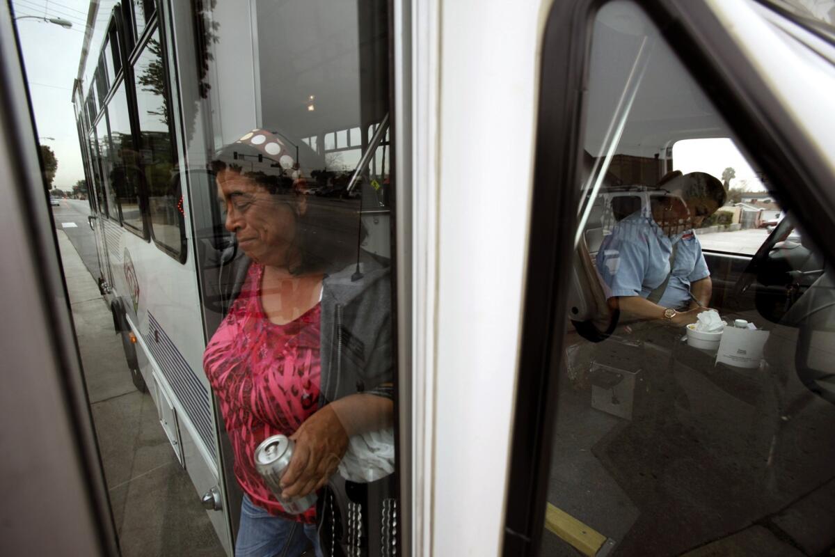 Asuncion Gomez, 55, exits the Dial-A-Ride bus as driver Laura Torres writes in her log. Some of the women enjoy tooling around town so much, they tell Torres to make their stop the last.