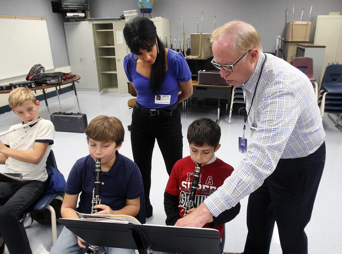 Music students Nicholas Rogers and Alex Paranyan, members of the Caesura Youth Orchestra, start to figure out their parts under the guidance of instructors Rachel Lopez and program founder Dave Ferguson during a rehearsal at Cerritos Elementary School in Glendale on Tuesday.