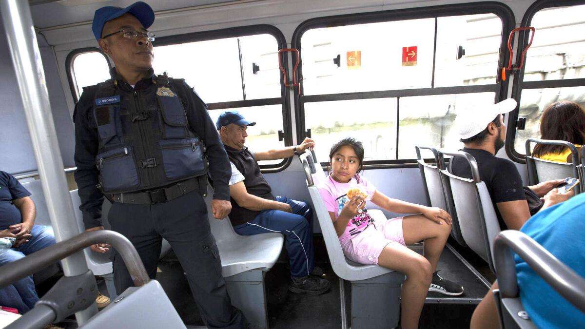 Una niña se sienta cerca de un agente de la policía en la parte trasera de un camión del transporte público, en Ciudad de México.