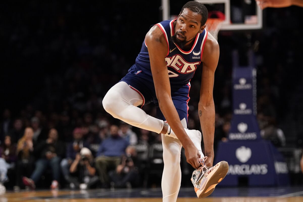Brooklyn Nets forward Kevin Durant puts his sneaker back on during the first half of the team's NBA basketball game against the Minnesota Timberwolves, Friday, Dec. 3, 2021, in New York. (AP Photo/Mary Altaffer)