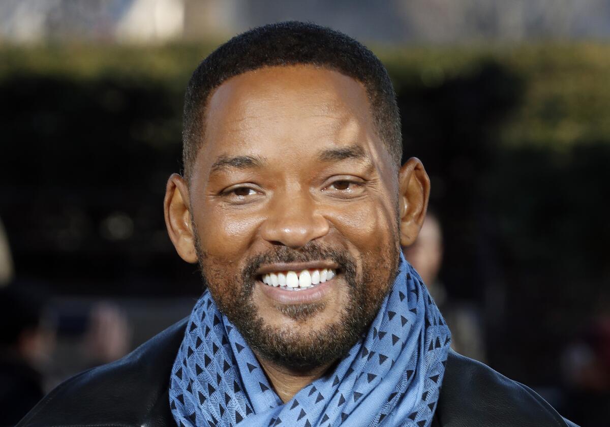Will Smith smiles while wearing a blue and black patterned scarf.