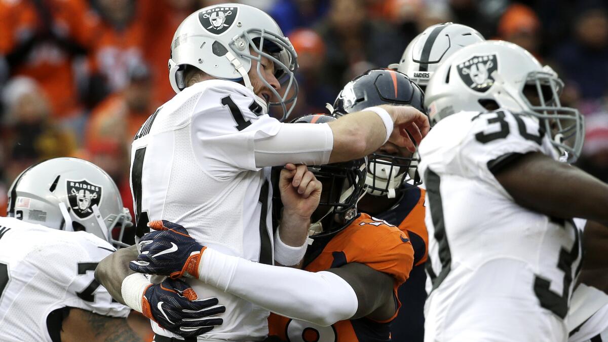 Raiders quarterback Matt McGloin is hit by Broncos linebacker Shaquil Barrett after throwing a pass during the first half Sunday.