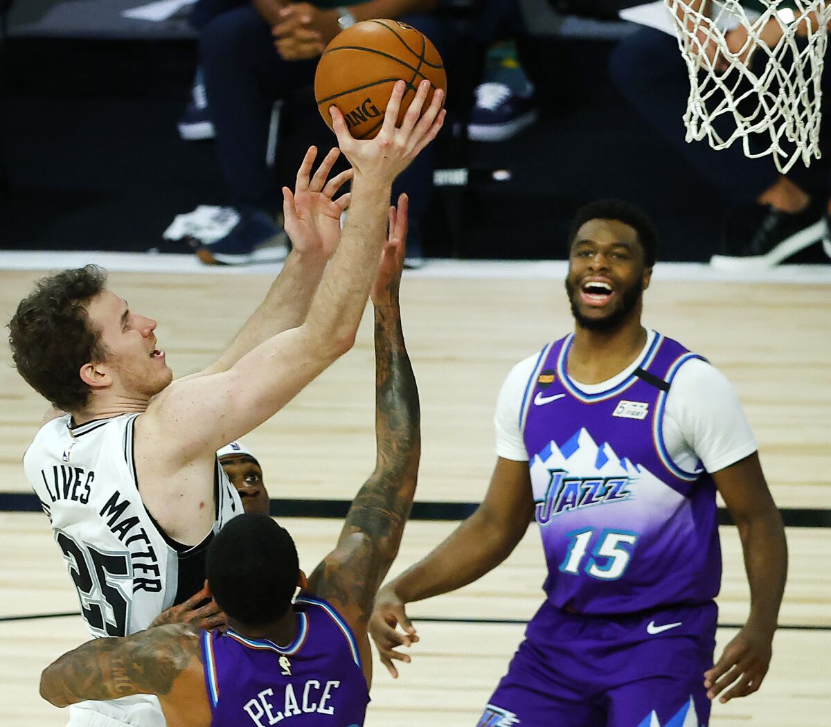 San Antonio Spurs' Jakob Poeltl drives to the basket between Utah Jazz's Jordan Clarkson, left, and Emmanuel Mudiay.