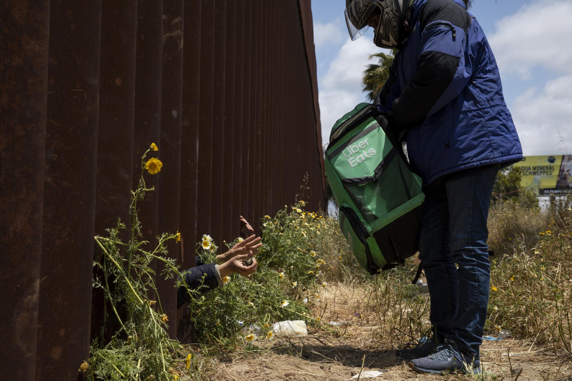 Los migrantes pagan sus pedidos de Uber Eats mientras esperan días entre los muros fronterizos