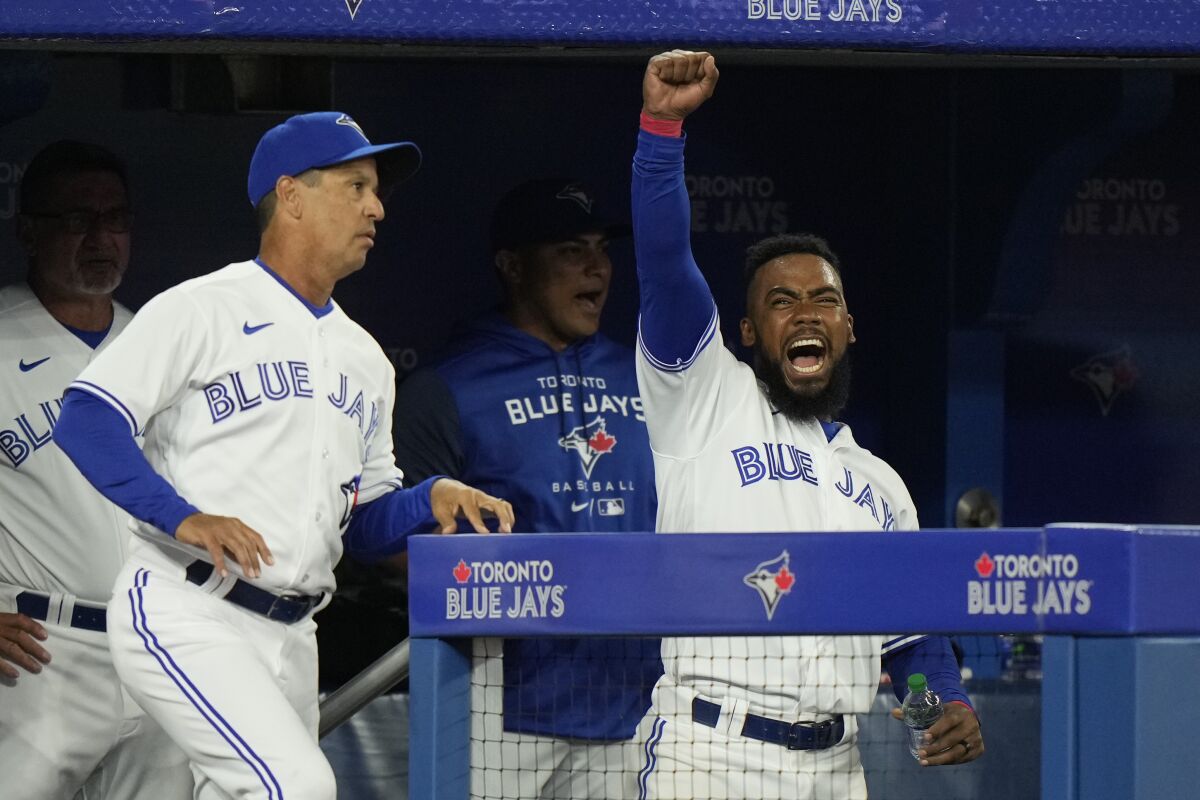 Toronto Blue Jays' Teoscar Hernandez, right, and manager Charlie Montoyo react in the dugout after a call at home plate was overturned during the seventh inning of the team's baseball game against the Texas Rangers on Friday, April 8, 2022, in Toronto. (Frank Gunn/The Canadian Press via AP)