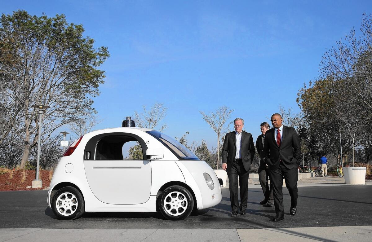 Google Chairman Eric Schmidt, left, and U.S. Transportation Secretary Anthony Foxx, right, walk around a Google self-driving car at the company's headquarters in Mountain View, Calif.