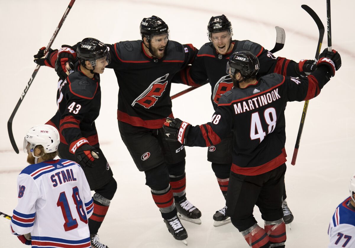 New York Rangers defenseman Marc Staal (18) skates away as Carolina Hurricanes left wing Jordan Martinook (48) is congratulated on his goal by teammates Morgan Geekie (43), Joel Edmundson (6) and Brock McGinn (23) during the second period of an NHL Stanley Cup playoff hockey game in Toronto, Monday, Aug. 3, 2020. (Frank Gunn/The Canadian Press via AP)