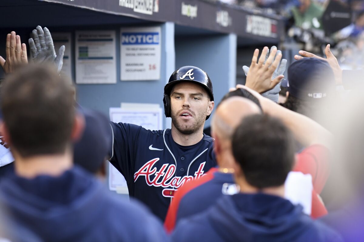 Former Braves star Freddie Freeman celebrates with teammates in the dugout after hitting a two-run home run 