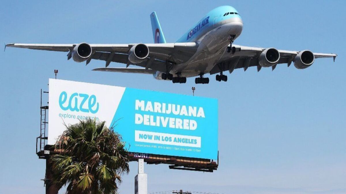 An airplane descends to land at Los Angeles International Airport above a billboard advertising the marijuana delivery service Eaze in July 2018.