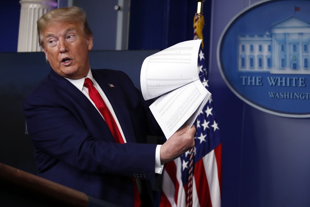 FILE President Donald Trump holds up papers as he speaks about the coronavirus in the James Brady Press Briefing Room of the White House on April 20, 2020, in Washington. Revelations that Trump took government records with him to Mar-a-Lago is a political headache for the former president and a potential legal one too. House investigators have launched an investigation, and the National Archives and Records Administration has reportedly asked the Justice Department to look into the matter. (AP Photo/Alex Brandon, File)
