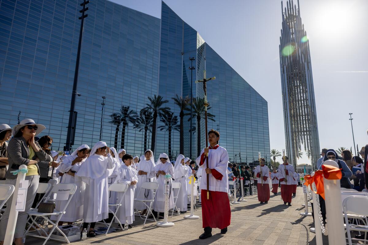 A procession begins outside a glass-walled cathedral in Garden Grove.