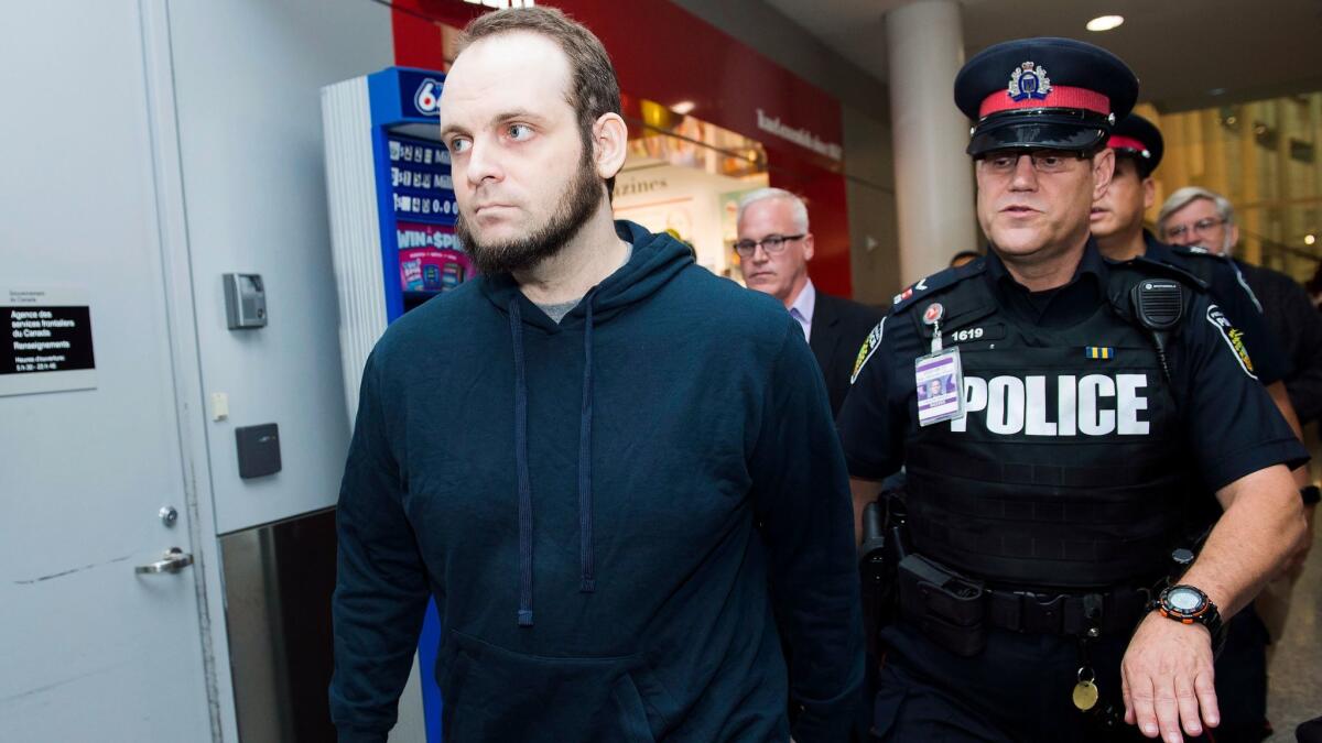 Joshua Boyle, left, gets a police escort after speaking to reporters at the airport in Toronto.