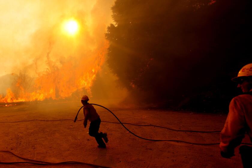 As firefighters mobilize, the Station blaze moves up a hill after leaping the highway. The conflagration devastated one of America's most-visited national forests.