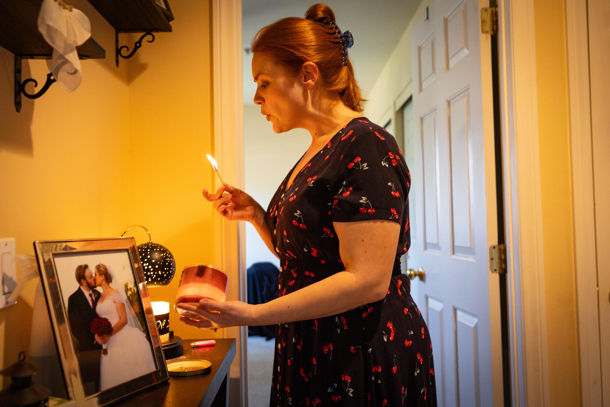  A woman lights a candle next to a photograph.