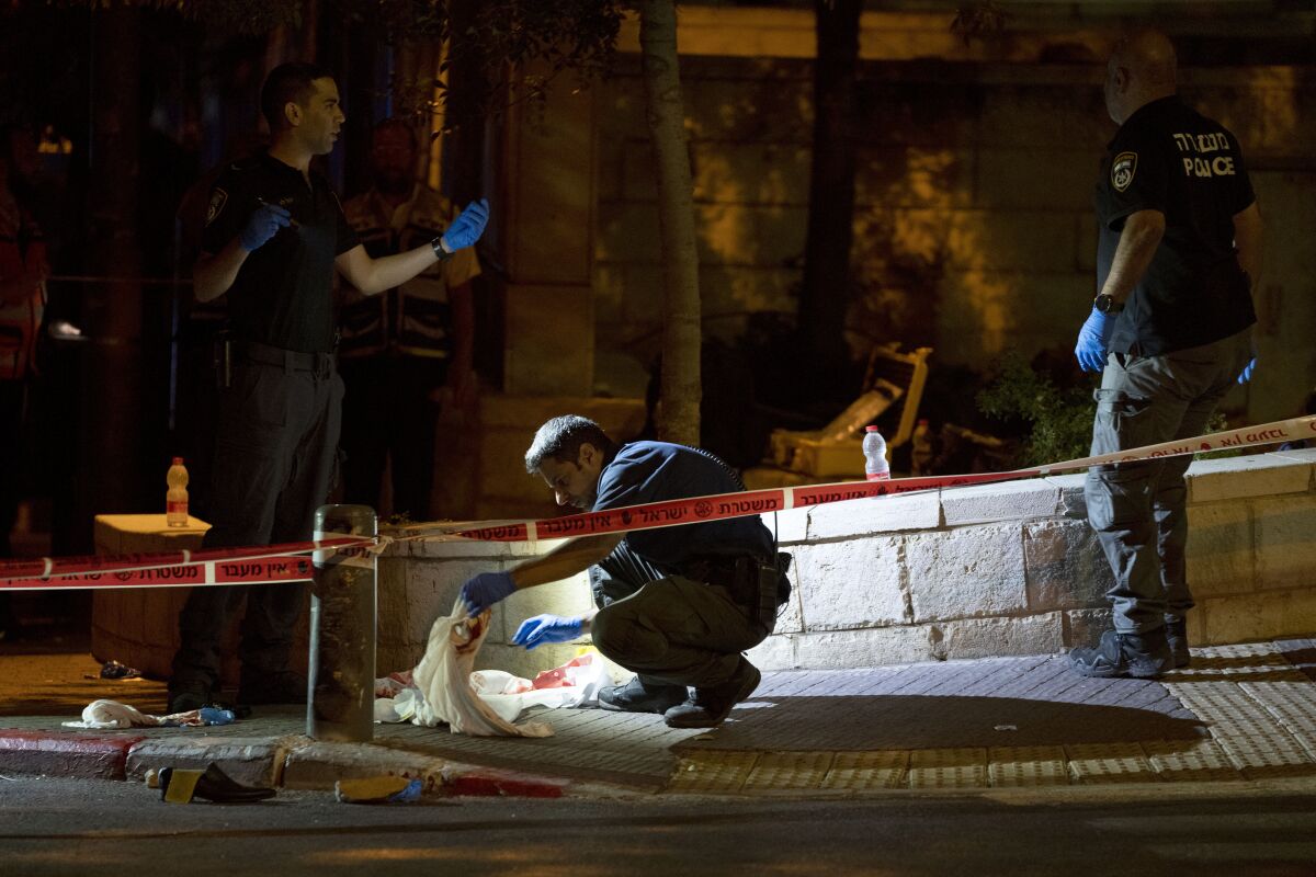 Israeli police crime scene investigators work at the scene of a shooting attack that wounded several Israelis near the Old City of Jerusalem, early Sunday, Aug. 14, 2022. Israeli police and medics say a gunman opened fire at a bus in a suspected Palestinian attack that came a week after violence flared up between Israel and militants in Gaza. (AP Photo/ Maya Alleruzzo)