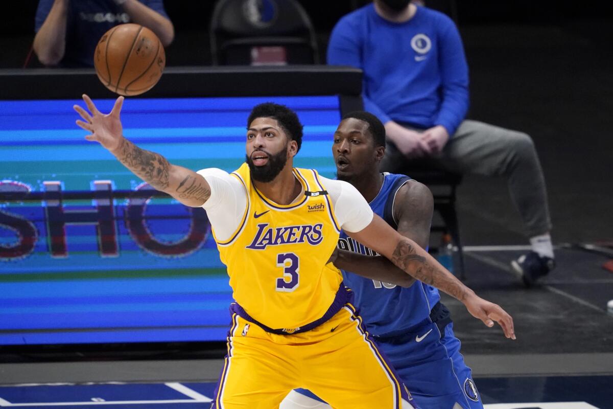 Lakers' Anthony Davis reaches out for a pass as Dallas Mavericks' Dorian Finney-Smith defends.