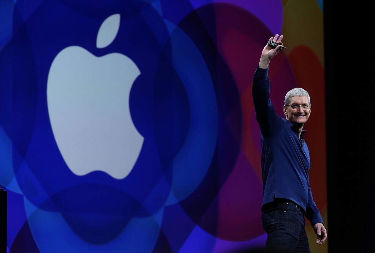 Apple Chief Executive Tim Cook smiles in front of the Apple logo.