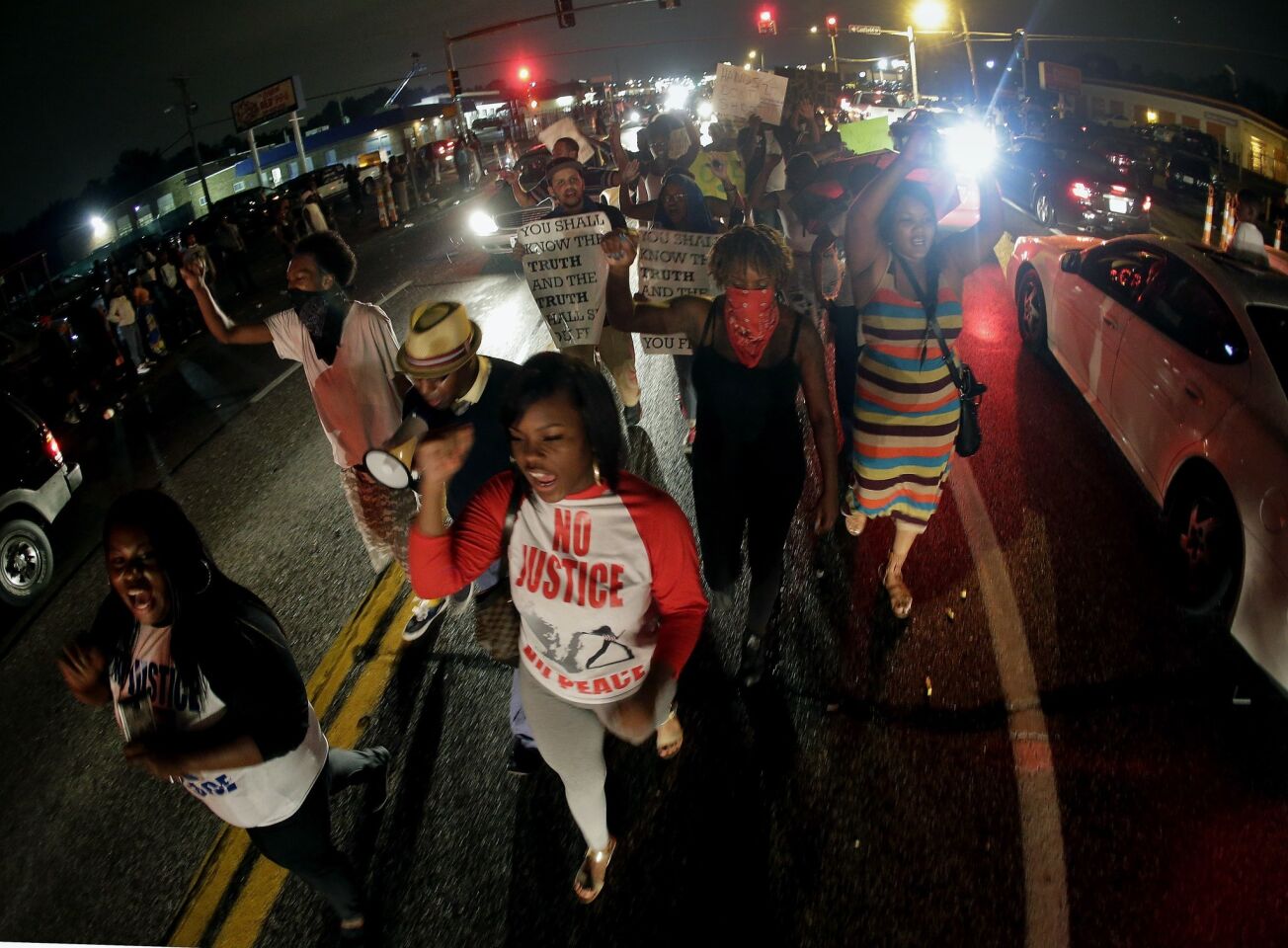 Protesters march on Aug. 15 down the middle of a street in front of a convenience store that was looted and burned after the shooting death of Michael Brown by police in Ferguson, Mo.