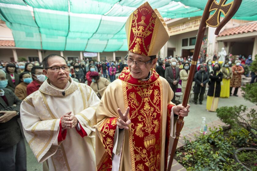 Most Rev. Thanh Thai Nguyen, auxiliary bishop of the Diocese of Orange, gestures to a parishioner during a processional into the Vietnamese Catholic Center in Santa Ana on Tuesday, February 1, during a mass to mark the Vietnamese Tet holiday.