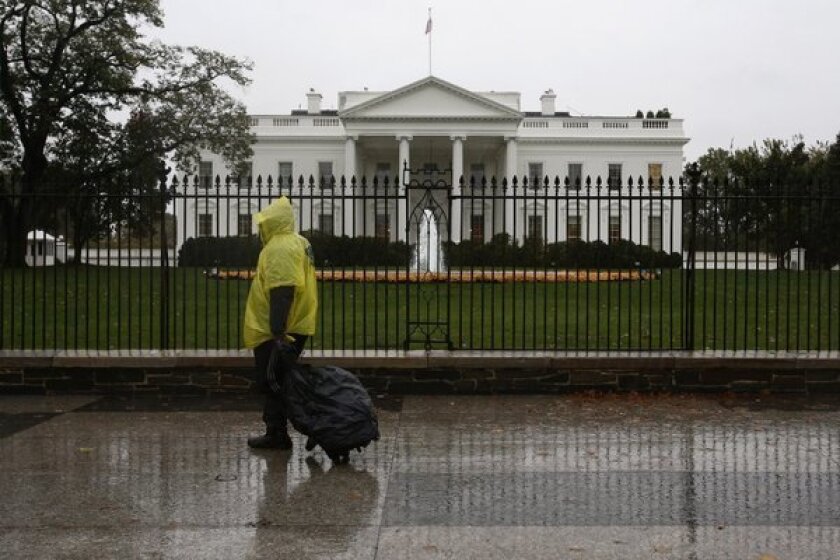 A man wearing a rain pouch walks past the White House in Washington during the approach of Hurricane Sandy. The nation's capital was largely deserted as the federal government and most businesses shut down.