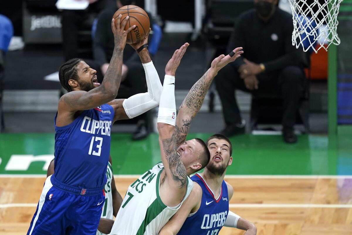 Paul George shoots against Boston Celtics center Daniel Theis as Clippers center Ivica Zubac looks on.