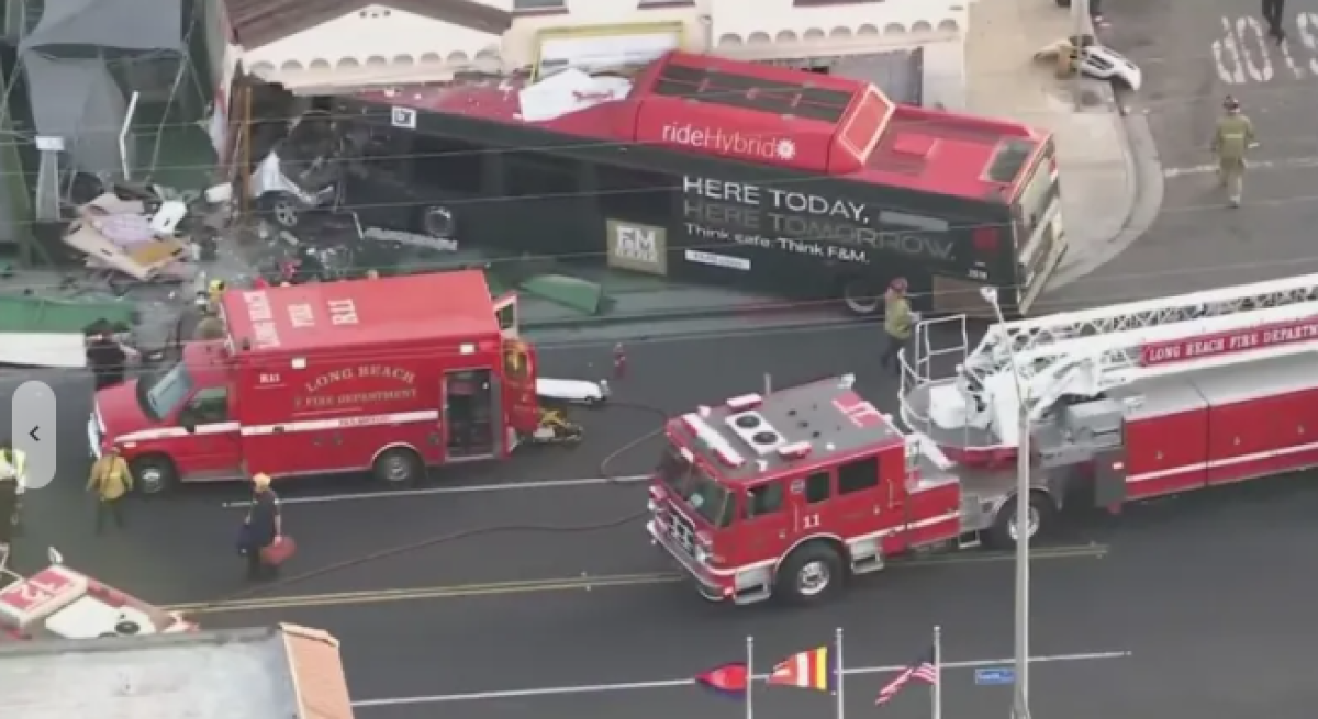 A firetruck and ambulance sit alongside a bus crashed into a building.