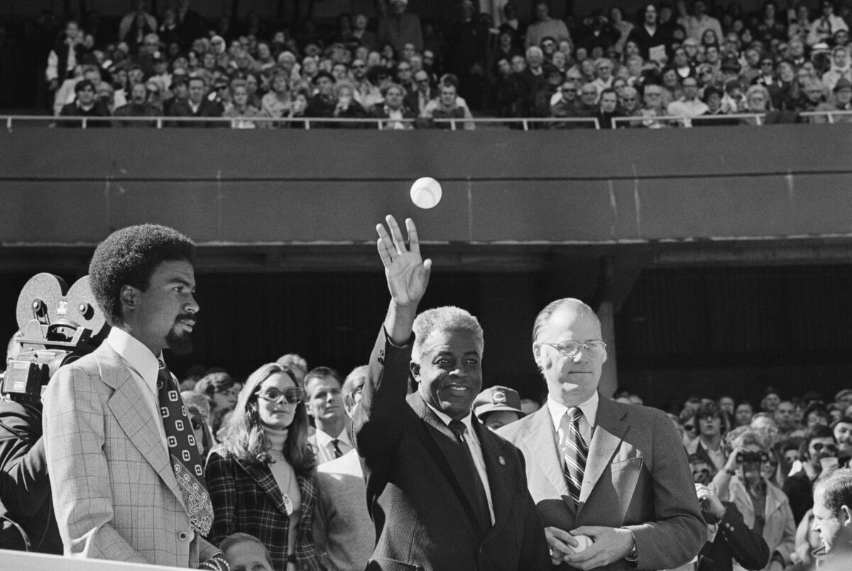 Jackie Robinson throws out the first ball as Baseball Commissioner Bowie Kuhn stands at his side in 1972.