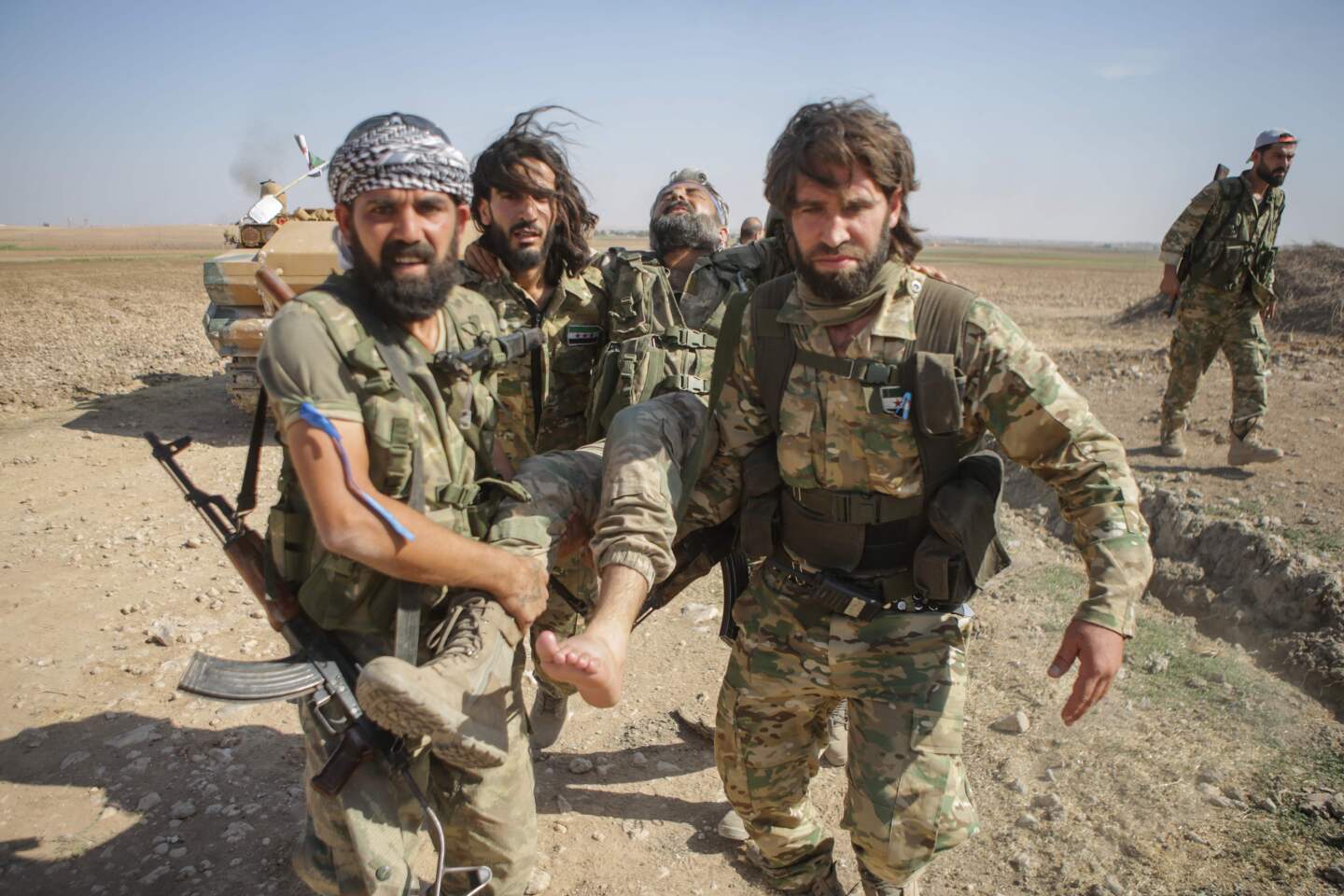 Turkish-backed Syrian fighters carry a fellow wounded fighter near the Syrian border town of Tal Abyad