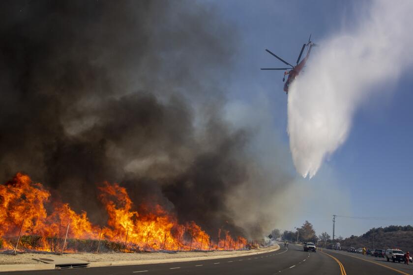 THOUSAND OAKS, CALIF. -- WEDNESDAY, OCTOBER 30, 2019: Helicopters drop water after inmate crews set backfires to heavy brush along Madera Rd. as firefighters try to keep the Easy fire from crossing the road into Thousand Oaks, Calif., on Oct. 30, 2019. (Brian van der Brug / Los Angeles Times)
