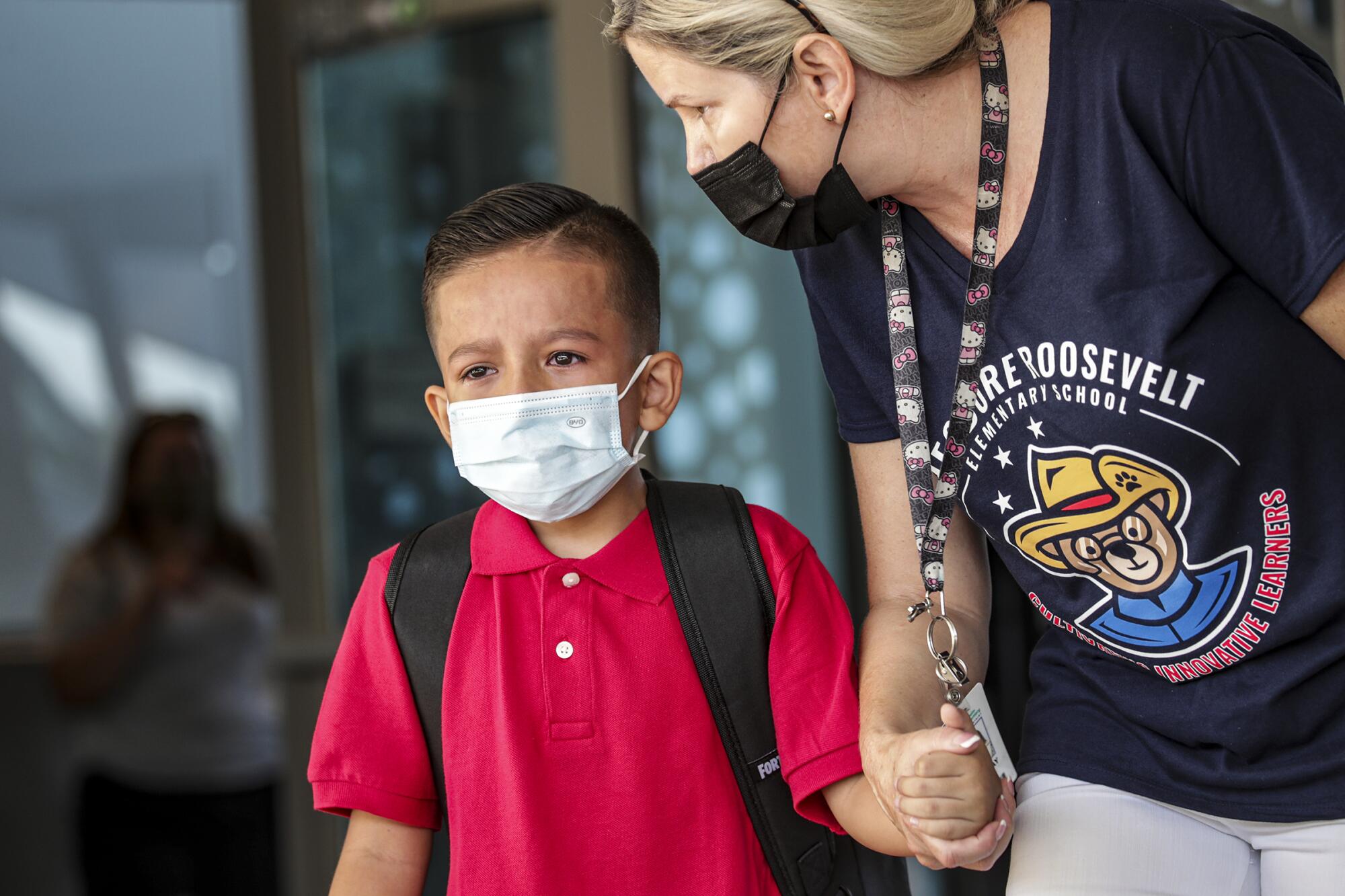 Jennifer Wray, right, leads Adam Pineda, 6, who missed his mother, to class at Theodore Roosevelt Elementary School.