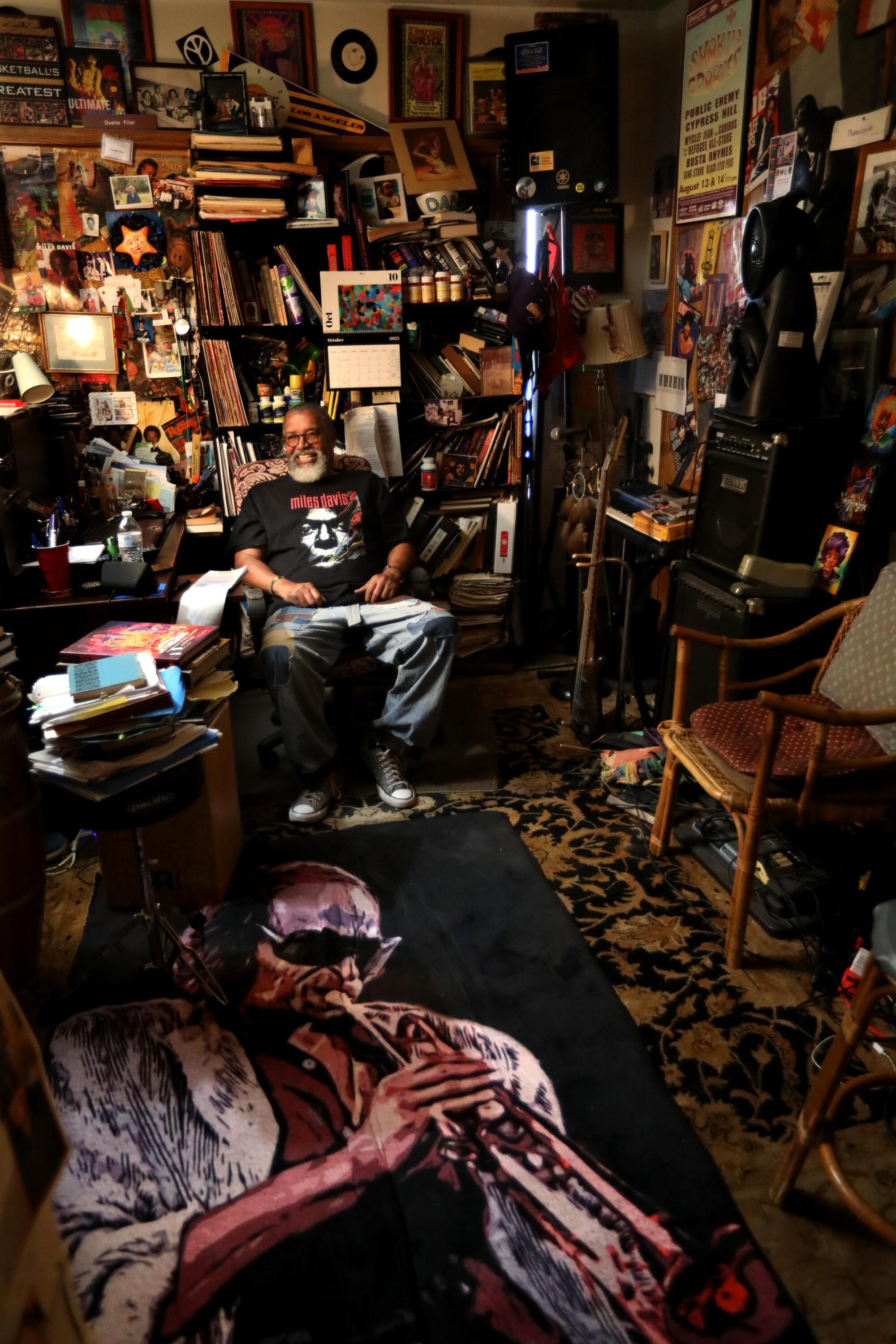 Мужчина сидит в своем домашнем офисе в окружении изображений музыкантов.