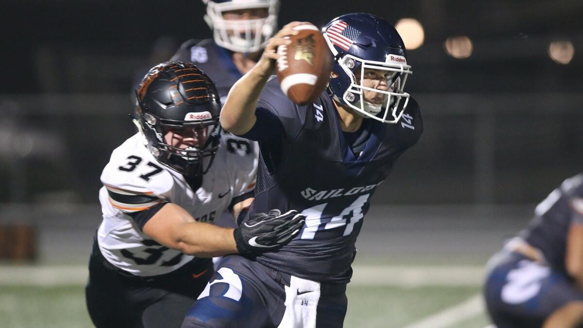 Newport Harbor High quarterback Cole Lavin is wrapped up by Huntington Beach linebacker John Gosney during a Sunset League opener on Friday.