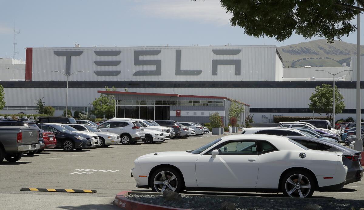 Vehicles are seen parked at the Tesla car plant in Fremont, Calif.